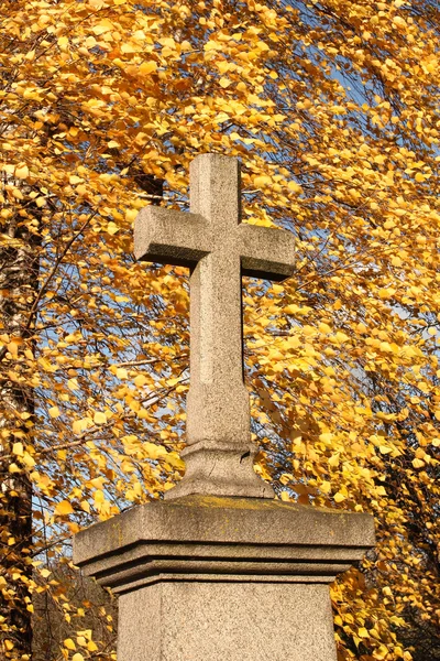 Kamenný kříž proti žluté listy — Stock fotografie