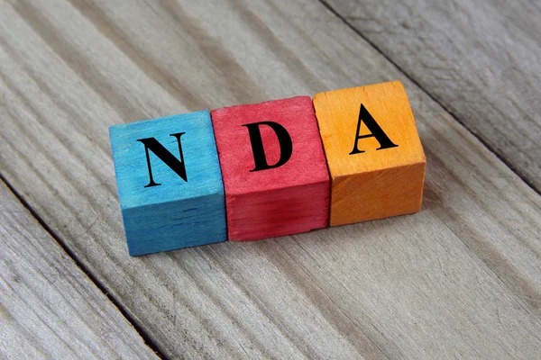 NDA (Non-dohoda odhalení) text na barevné dřevěné kostky — Stock fotografie