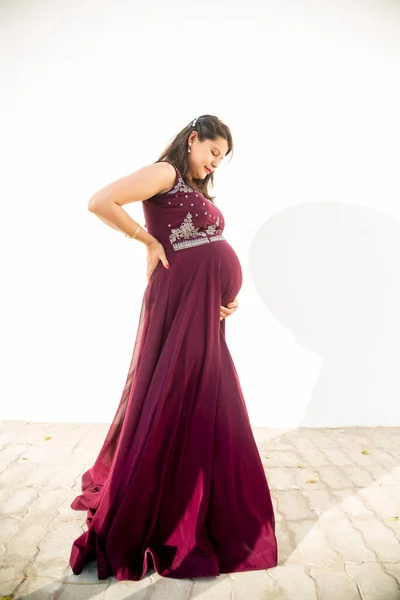 Mladá Těhotná Žena Při Pohledu Břicho Stojící Proti Bílému Pozadí — Stock fotografie
