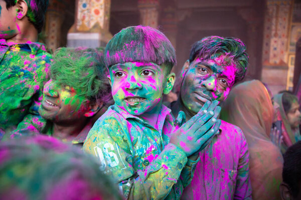 Джодхпур, Раджастха, Индия - 20 марта 2020 года: Молодой индийский отец и сын празднуют праздник Холи, закрыв лицо цветным порошком.