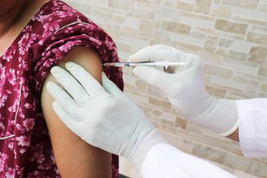 Doktor, Covid-19 ya da Coronavirus aşısını COVISHIELD / COVAXIN Dose adlı bir hastaya enjekte etmek için şırıngayı kullanıyor..