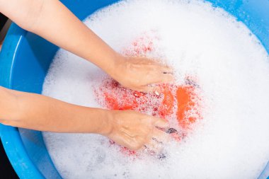 Yakın çekimde genç Asyalı kadın leğende çamaşır suyu, sabunlu köpük suyu, stüdyo çekimi arka planı, çamaşır konsepti...