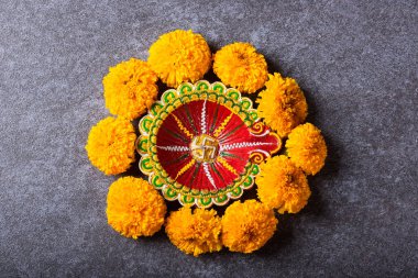 Üst tepedeki kil Diya 'yı ya da yağ lambasını ya da sarı çiçeği aydınlatıyor, stüdyo çekimleri somut arka planda, Hinduizm rangolisinin dekorasyonu, Mutlu Deepavali ya da Diwali festivali konsepti