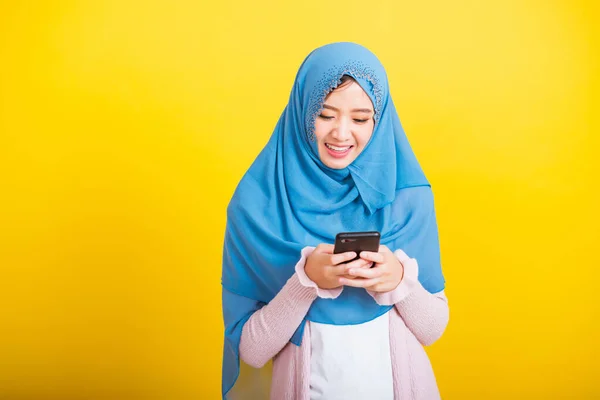 アジア系ムスリムアラブ人 幸せな美しい若い女性の肖像 イスラームという宗教的な摩耗ベールヒジャーブ面白い笑顔彼女は黄色の背景に隔離された携帯電話の読書ソーシャルメディアを使用して — ストック写真