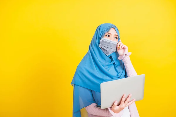 アジア系イスラム教徒アラブ人 幸せな美しい若い女性の肖像イスラム教の宗教的な摩耗ベールヒジャーブと顔のマスク彼女は病気のコロナウイルスを隔離保護するラップトップコンピュータを保持し 疑問を考えて — ストック写真