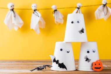 Komik Cadılar Bayramı süsleme partisi, Bebek beyaz hayaletler korkunç suratlar asma ve cadılar bayramı el sanatları kağıt bardak hayaleti, stüdyo resmi izole edilmiş, Mutlu bayramlar el işi konsepti