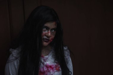 Evdeki karanlık bir odada korkunç kötü kadın hayaleti. Kan içindeki dişi zombi korkunçtur. Terk edilmiş binaya musallat oldu. Mutlu Cadılar Bayramı festivali konsepti.