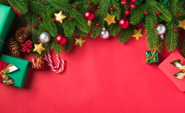 Noel arkaplanı, üzerinde yeşil köknar ağacı dalları ve dekorasyon hediye kutusu olan tebrik kartı sunar. Kırmızı masa arkaplanında fotokopi alanı olan Xmas bayramı kutlaması sezonu.