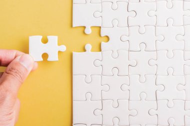 Top view düz konum son parça beyaz kağıt yapboz oyunu çözülmesi için yerleştirilen son parçalar tam görev, stüdyo çekimi sarı arkaplan, quiz hesaplama konsepti
