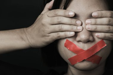 Asyalı bir kadın siyah arka planda kırmızı bantla gözlerini bağlıyor. Konuşma özgürlüğü sansürü ve konuşmayı durdurmak, Uluslararası İnsan Hakları Günü