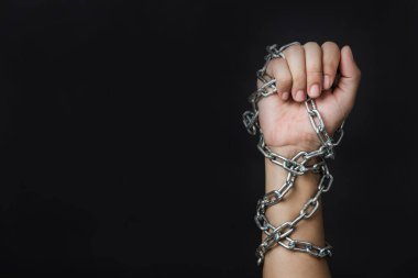 Kadın, siyah arka planda zincire vurulmuş, insan ticareti ve istismarı, Uluslararası İnsan Hakları Günü