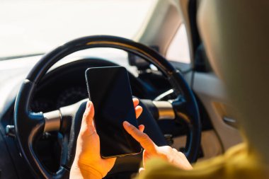 Bir arabanın içindeki Asyalı kadın ve sabah otoyolda arabayı sürerken cep telefonunun boş ekranında dokunmatik ekran kullanıyor. Ulaşım ve araç konseptine gitmek için navigasyon yeri buluyor.