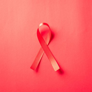 Kırmızı kurdele sembolü HIV, AIDS kanseri gölgeli farkındalık, kırmızı arka planda izole edilmiş stüdyo çekimi, sağlık sigortası konsepti, Dünya AIDS Günü