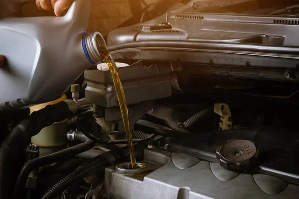 Mechanic in service to repair the car, refueling and pouring from bottle to change lubricant oil at maintenance repair service station, Energy fuel automotive concept