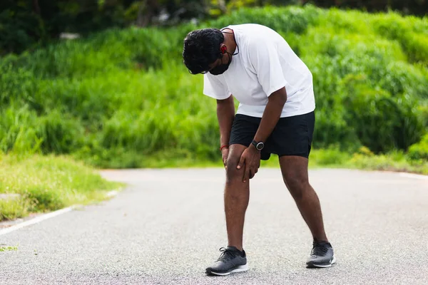 Kapatın Asyalı genç spor koşucusu, saat takın, el ele tutuşun, el ele tutuşun, koşarken diz çökün, sağlık parkında koşun, spor konseptinden dolayı sağlıklı egzersiz sakatlığı.