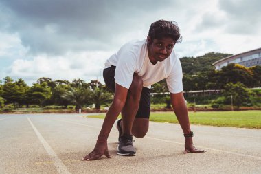 Asyalı genç sporcu spor koşucusu siyah adam ayak ayakkabısı giyiyor. Koşu bandında koşmaya hazır. Bir adım öne doğru.