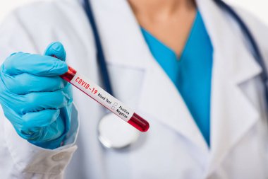 Beyaz üniformalı doktor Coronavirus test tüpü taşıyan bir maske takıyor. Klinik bir laboratuvarda, beyaz, ilaç COVID-19 salgın konseptini analiz etmek için kan örneği alınıyor.