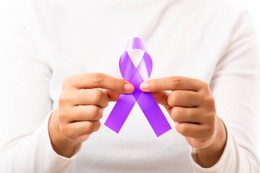 Ulusal Epilepsi veya Alzheimer Hastalıkları Günü. Elinde pankreas kanseri, epilepsi farkındalığı ve dünya Lupus Günü ve dünya kanserinin izole edilmiş beyaz arka plan sembolü olan mor kurdele tutan genç bir kadın.