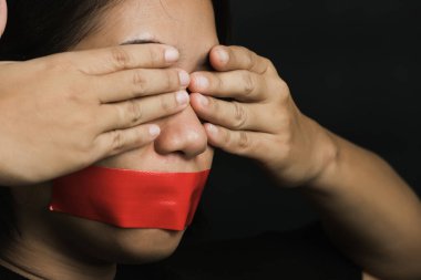 Asyalı bir kadın siyah arka planda kırmızı bantla gözlerini bağlıyor. Konuşma özgürlüğü sansürü ve konuşmayı durdurmak, Uluslararası İnsan Hakları Günü