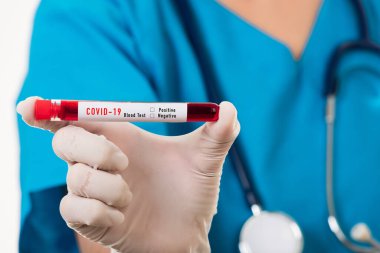 Mavi üniformalı hemşire laboratuarda beyaz arka planda izole edilmiş Coronavirus test kanını, COVID-19 ilaç salgın konseptini incelemek için bir maske takıyor.