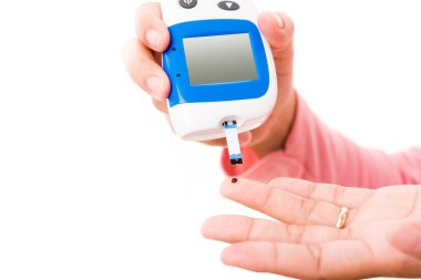Glikoz seviyesini ölçen elleri olan kadın, beyaz arka planda izole edilmiş yüksek kan şekeri diyabeti ve glisemik sağlık konseptini gözlemliyor ve kontrol ediyor.