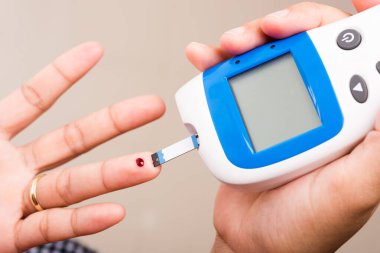 Kapalı Eller Glikoz seviyesini ölçen kadın evde glukometre parmak kan ile kontrol yüksek kan şekeri diyabeti ve glisemik sağlık konseptini izliyor ve kontrol ediyor