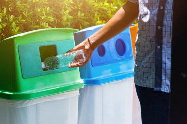 Seçici odak noktası siyah adamın boş plastik su şişesini çöp veya çöp kutusuna, çevresel geri dönüşüm konseptine atması. 
