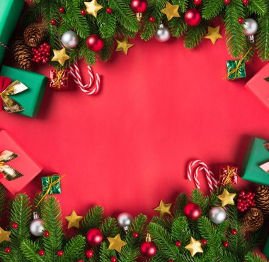 Noel arkaplanı, üzerinde yeşil köknar ağacı dalları ve dekorasyon hediye kutusu olan tebrik kartı sunar. Kırmızı masa arkaplanında fotokopi alanı olan Xmas bayramı kutlaması sezonu.