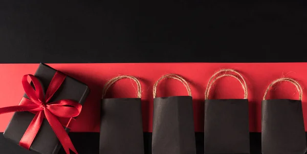 黑色星期五购物节及节礼概念 礼品盒包裹黑纸 红色蝴蝶结礼物及购物袋 工作室拍摄孤立在红色和黑色背景 — 图库照片