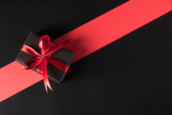 黑色星期五购物节及节礼的概念 礼品盒包装黑纸和红色蝴蝶结带礼物 工作室拍摄孤立在红色和黑色背景下 — 图库照片