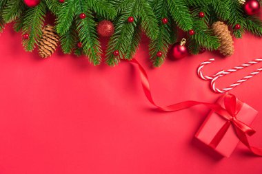 Noel tatili arkaplanı hediye kutusu süslemeleri üst görünüm köknar ağacı dalları ve kırmızı masa arkaplanındaki Xmas süslemeleri.