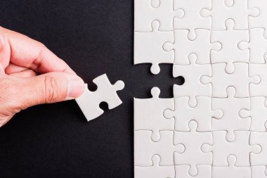 Top view düz konum son parça beyaz kağıt yapboz oyunu çözülmesi için yerleştirilen son parçalar tam bir görev, stüdyo çekimi siyah arka plan, quiz hesaplama konsepti