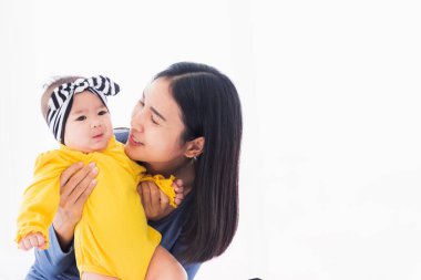 Güzel Asyalı bir annenin portresi, yeni doğmuş bebeğiyle evde oynayıp gülümsüyor ebeveyn anne ve küçük çocuk yatak odasında dinleniyor, aile birlikte eğleniyor.