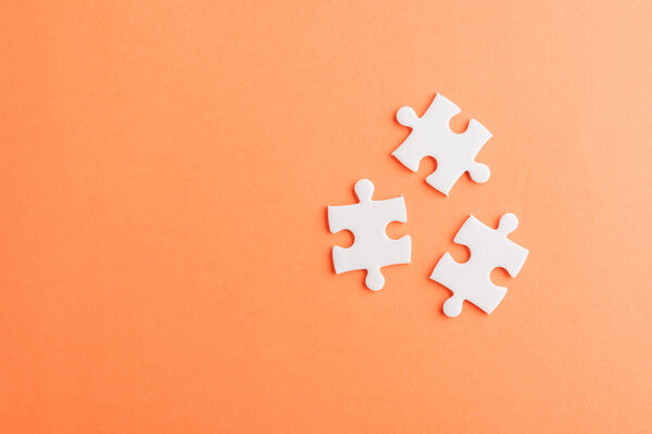 Top view flat lay of three paper plain white jigsaw puzzle game last pieces for solve, studio shot on an orange background, quiz calculation concept