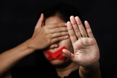 Ağzı kırmızı bantla saran ve el işaretini gösteren kadın siyah arka planda şiddet ve istismarı, insan ticaretini ve istismarı, Uluslararası İnsan Hakları Günü 'nü durdurdu.