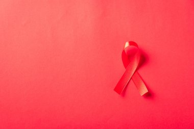 Kırmızı kurdele sembolü HIV, AIDS kanseri gölgeli farkındalık, kırmızı arka planda izole edilmiş stüdyo çekimi, sağlık sigortası konsepti, Dünya AIDS Günü
