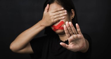 Ağzı kırmızı bantla saran ve el işaretini gösteren kadın siyah arka planda şiddet ve istismarı, insan ticaretini ve istismarı, Uluslararası İnsan Hakları Günü 'nü durdurdu.