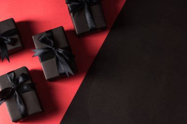 Kara Cuma alışveriş konsepti, siyah kağıt ve siyah kurdeleye sarılı hediye kutusu manzarası, kırmızı ve koyu arka planda izole edilmiş stüdyo çekimi.