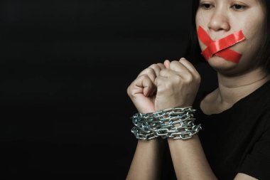 Asyalı bir kadın kırmızı yapıştırıcı bantla gözlerini bağlıyor ve elleri bağlı tercüman zinciri siyah arka planı var. Konuşma özgürlüğü sansürü ve konuşmayı durdurmak, Uluslararası İnsan Hakları Günü