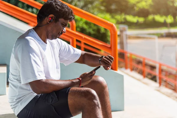 아시아인젊은 시계를 착용하고 야외에서 기술로 스마트폰 결과에 동기화 — 스톡 사진