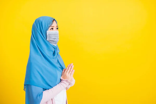 アジアのイスラム教徒アラブ 美しい若い女性の肖像イスラム教の宗教的な摩耗ベールヒジャーブと顔のマスクは 隔離された黄色の背景にアイド フィトルを祈る手を上げる検疫疾患コロナウイルスを保護します — ストック写真