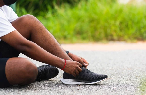中国日报 的报道 近段时间内 亚洲田径运动员 黑人男子坐在鞋带上 试穿跑鞋 准备慢跑 在户外跑步 进行健康锻炼 — 图库照片