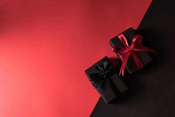 黑色星期五购物理念 顶部的礼品盒包装黑纸和黑色蝴蝶结带 工作室拍摄孤立在红色和黑色背景 — 图库照片