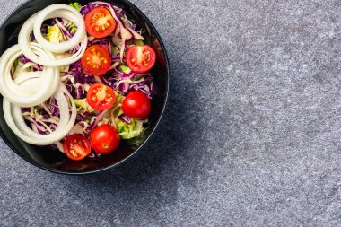 Sağlıklı renkli salata kasesinin, domatesli taze karışık yapraklı, çimento taş masa zemininde sebzeli, sağlıklı salata atıştırmalığı diyet kilo verme konsepti.
