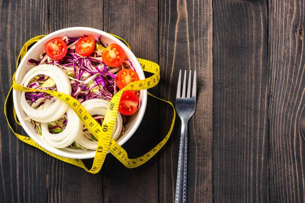 Sağlıklı renkli salata kasesinin üst görüntüsü domatesli taze sebzeli sebze ve siyah ahşap arka planda şerit, sağlıklı salata atıştırmalığı diyet kilo kaybı konsepti.