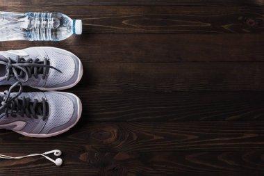 Spor ayakkabıları, kulaklıklar ve siyah tahta masa zemininde su şişesi, spor salonundaki gri spor ayakkabıları ve aksesuar ekipmanları, sağlıklı egzersiz, aktif yaşam tarzı diyet konsepti