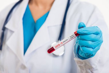 Beyaz üniformalı doktor Coronavirus test tüpü taşıyan bir maske takıyor. Klinik bir laboratuvarda, beyaz, ilaç COVID-19 salgın konseptini analiz etmek için kan örneği alınıyor.