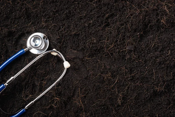 Black land for plant background and doctor stethoscope, Top view of Handprint on fresh soil with mulch for gardening texture, Concept of global pollution, World Soil Day and Save world conserve