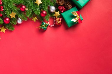 Noel arkaplanı, üzerinde yeşil köknar ağacı dalları ve dekorasyon hediye kutusu olan tebrik kartı sunar. Kırmızı masa arkaplanında fotokopi alanı olan Xmas bayramı kutlaması sezonu.