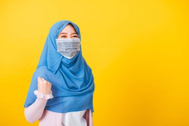 Asyalı Müslüman Arap, mutlu genç kadın portresi İslamiyet peçeli başörtüsü takıyor ve yüz maskesi takıyor. Koronavirüs hastalığından kurtulduktan sonra mutlu bir şekilde el kaldırın.